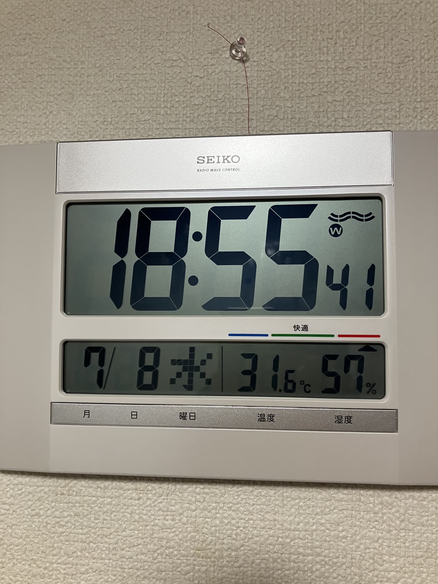 壁掛け時計の上に赤い糸で落下防止を付けた例