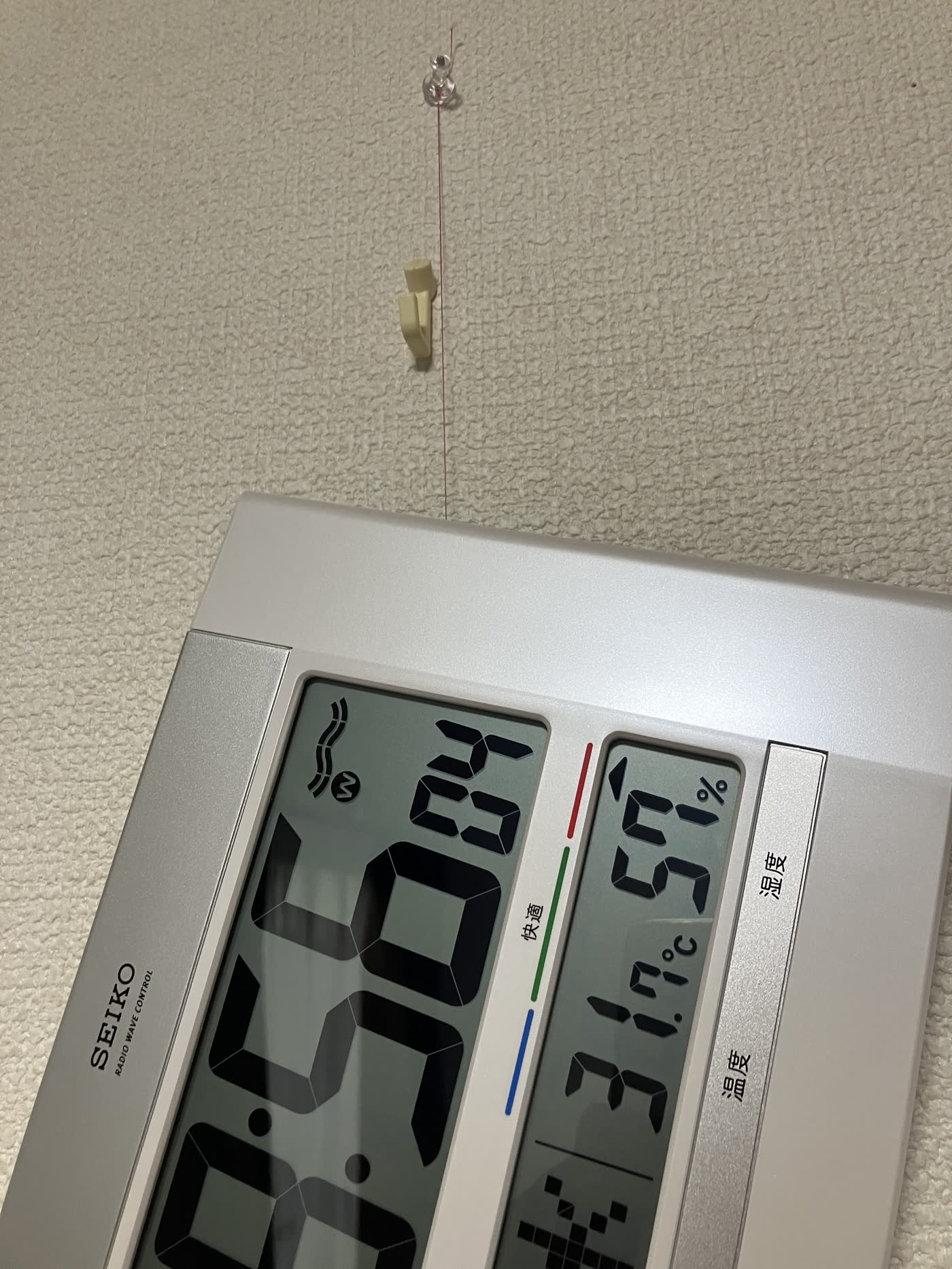 ピンと糸で壁掛け時計を支えている例